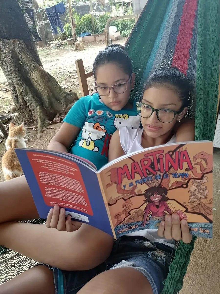 Two girls reading Martina y el Puente en el Tiempo in a hammock